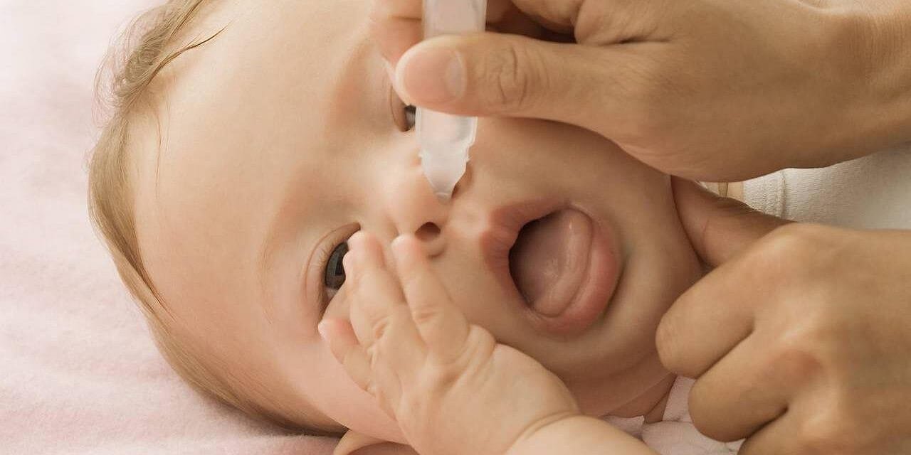 Khi vệ sinh mũi, nên đặt trẻ nằm nghiêng sang một bên.