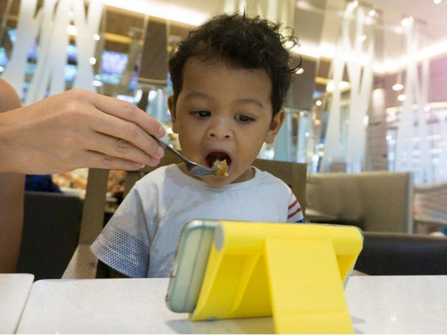TRẺ NHỎ VỪA ĂN VỪA DÁN MẮT VÀO MÀN HÌNH ĐIỆN THOẠI CẦM TAY