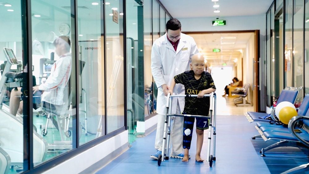 Bé Minh tập đi bằng dụng cụ hỗ trợ sau phẫu thuật