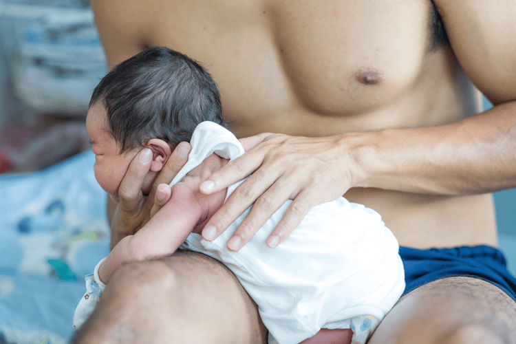 Đặt bé nằm sấp ngang trên đùi